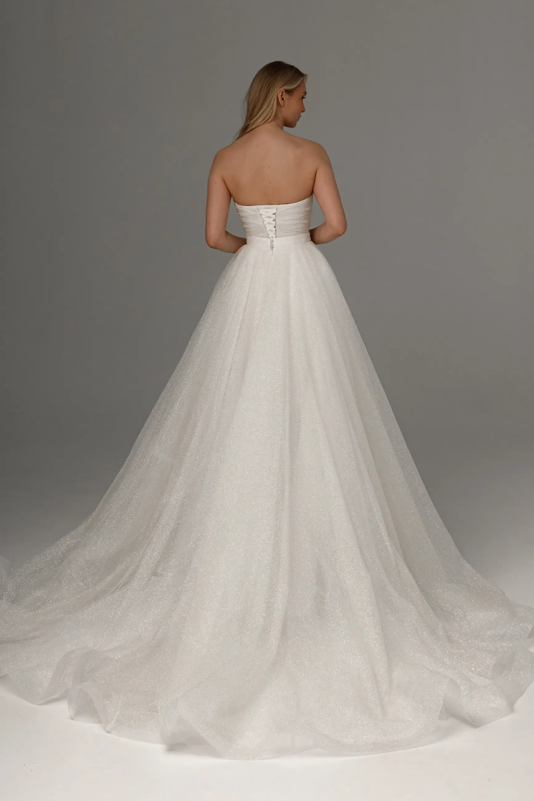 model is wearing a strapless ball gown wedding dress with a glitter tulle skirt