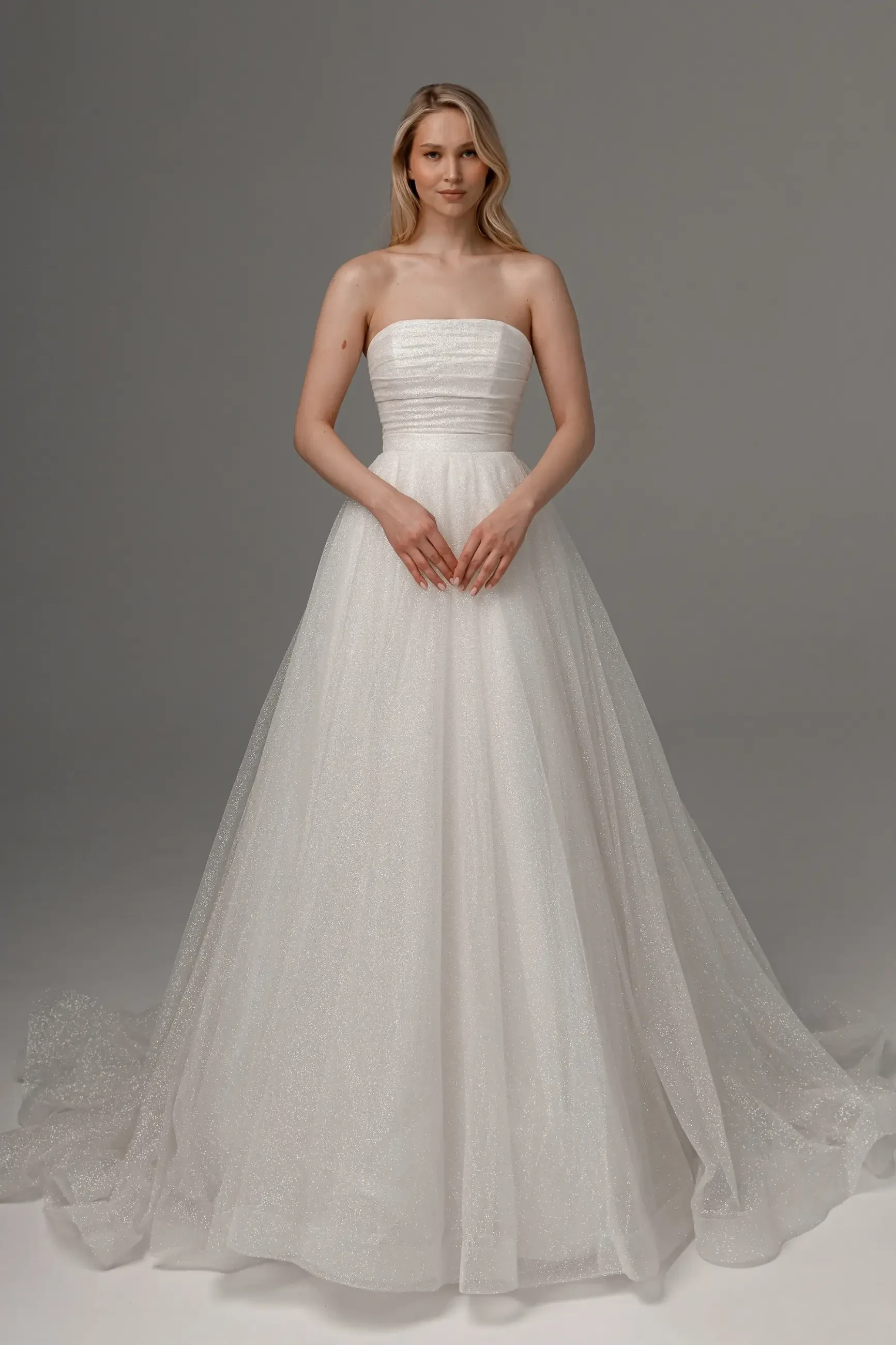 model is wearing a strapless ball gown wedding dress with a glitter tulle skirt