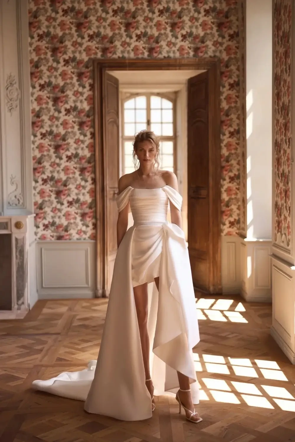 model is wearing a mini bridal gown with an optional overskirt
