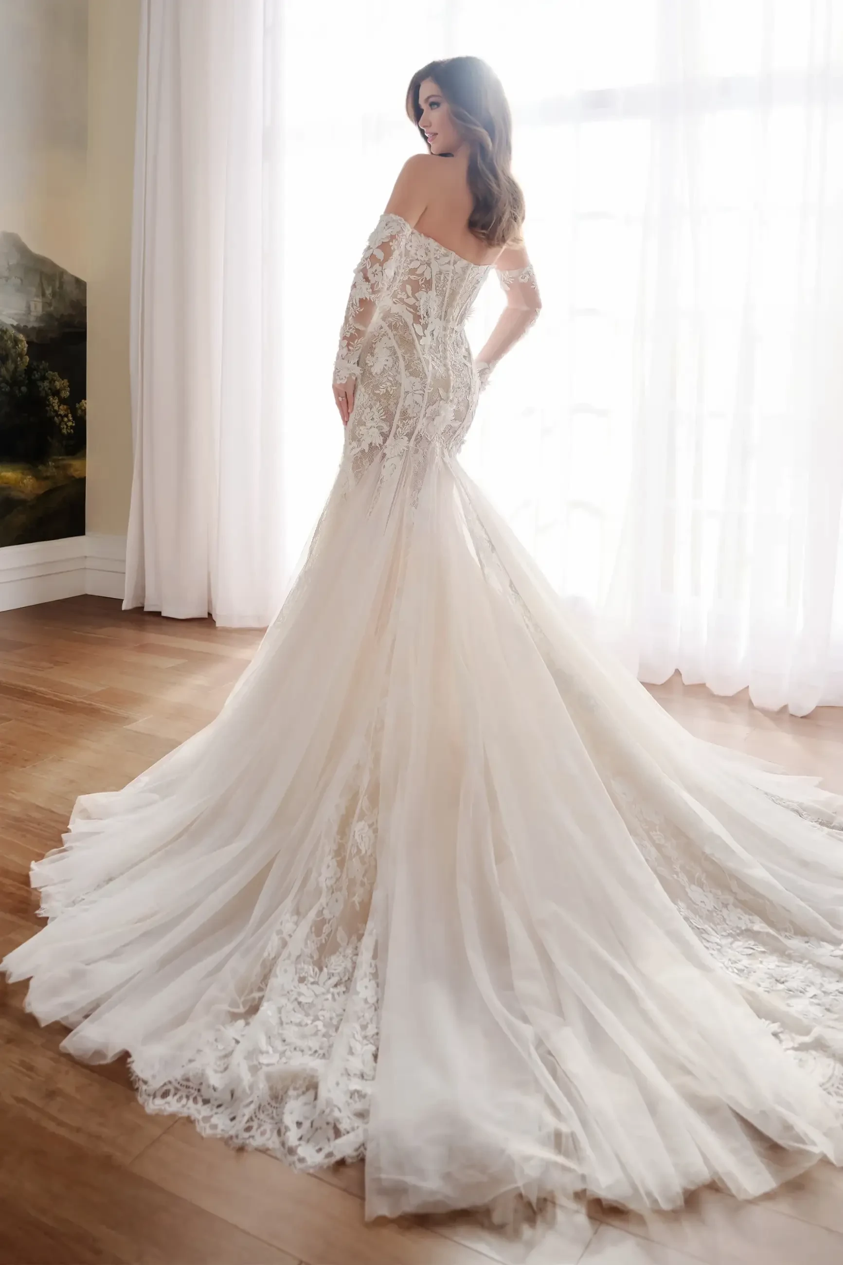 model is wearing a lace off the shoulder fit and flare bridal gown 