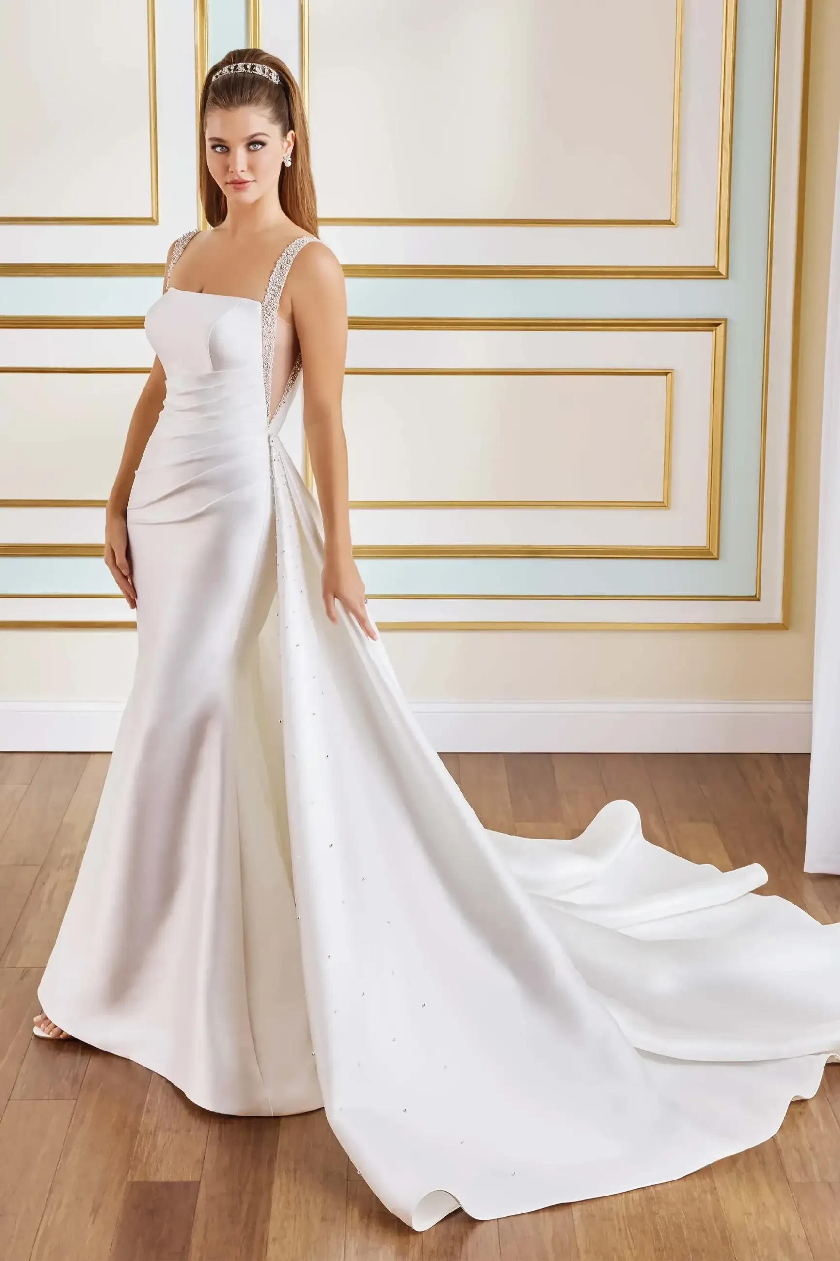 model is wearing a sleeveless sleek fit and flare wedding dress with a detachable train